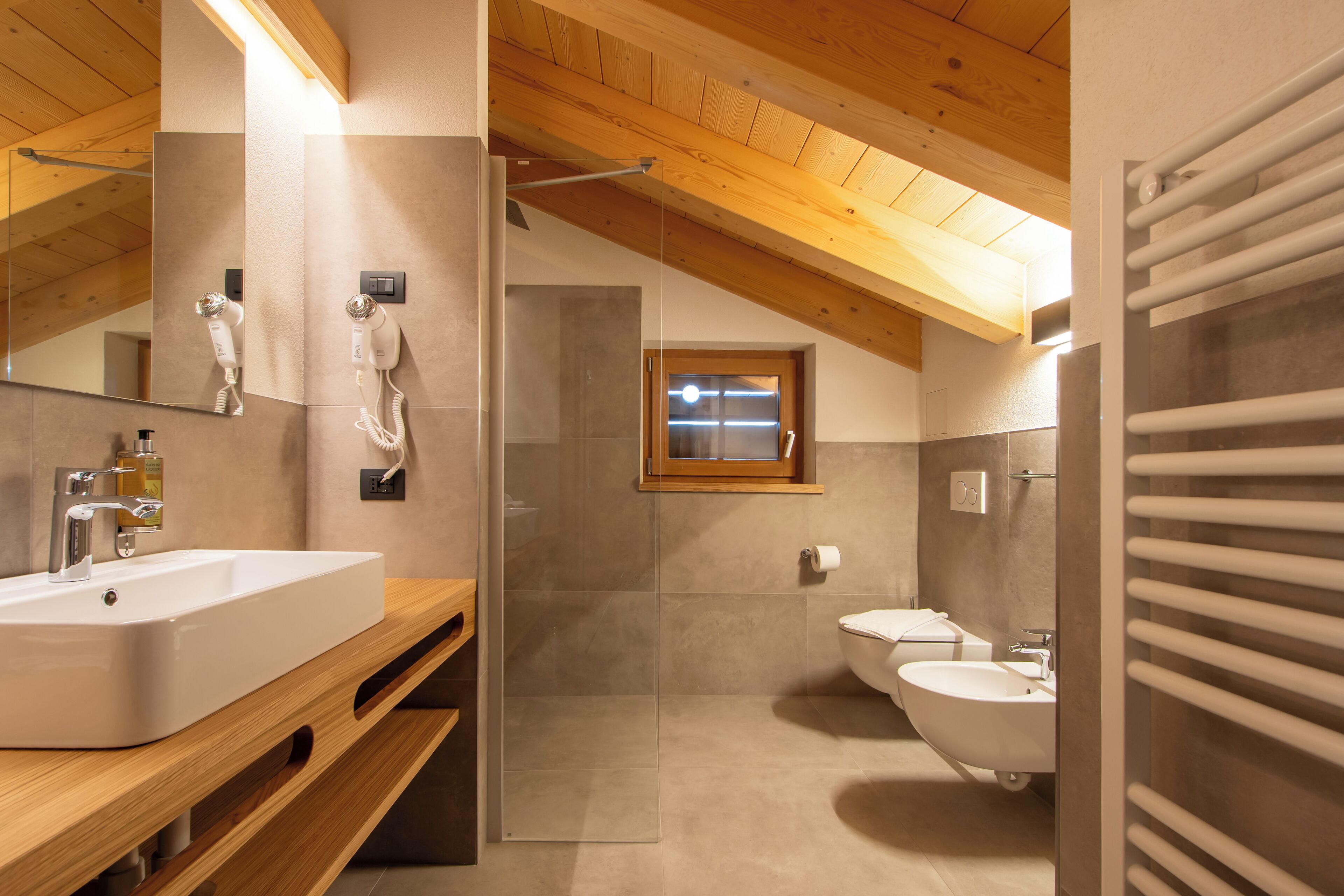 A modern bathroom with a wooden ceiling, a large mirror, a sink, a toilet, and a shower area.