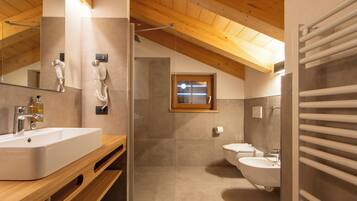 A modern bathroom with a wooden ceiling, a large mirror, a sink, a toilet, and a shower area.