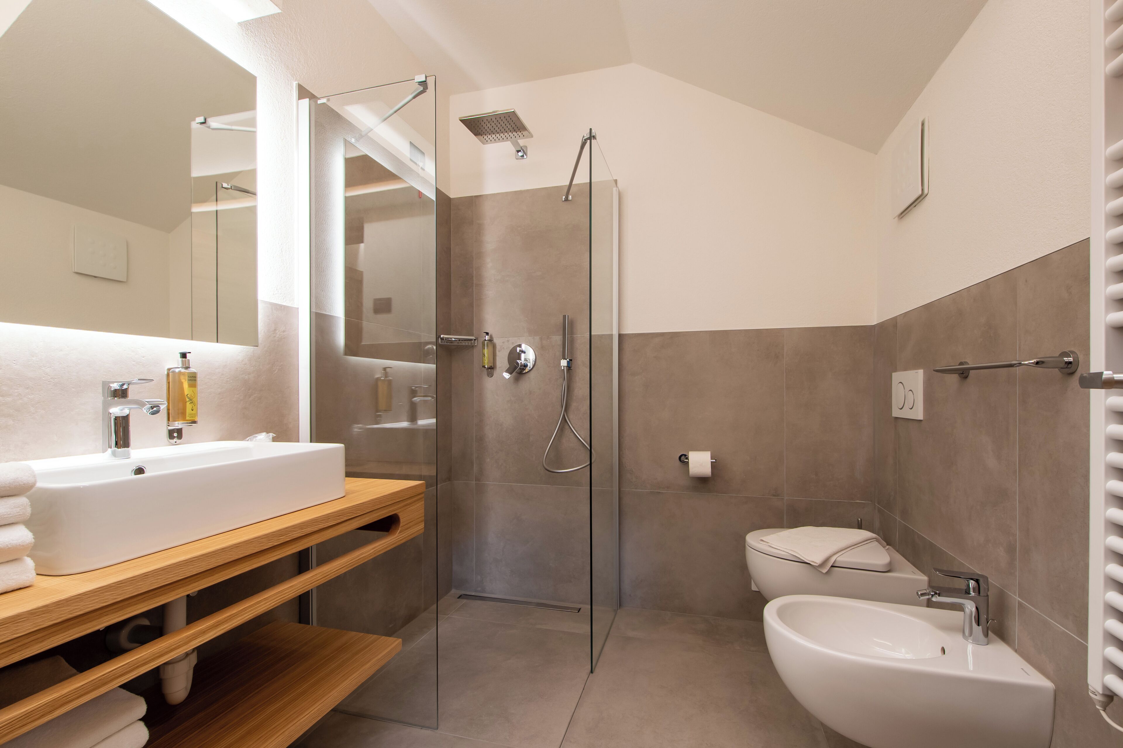 A modern bathroom with a large mirror, a shower enclosure, a sink, and a toilet.