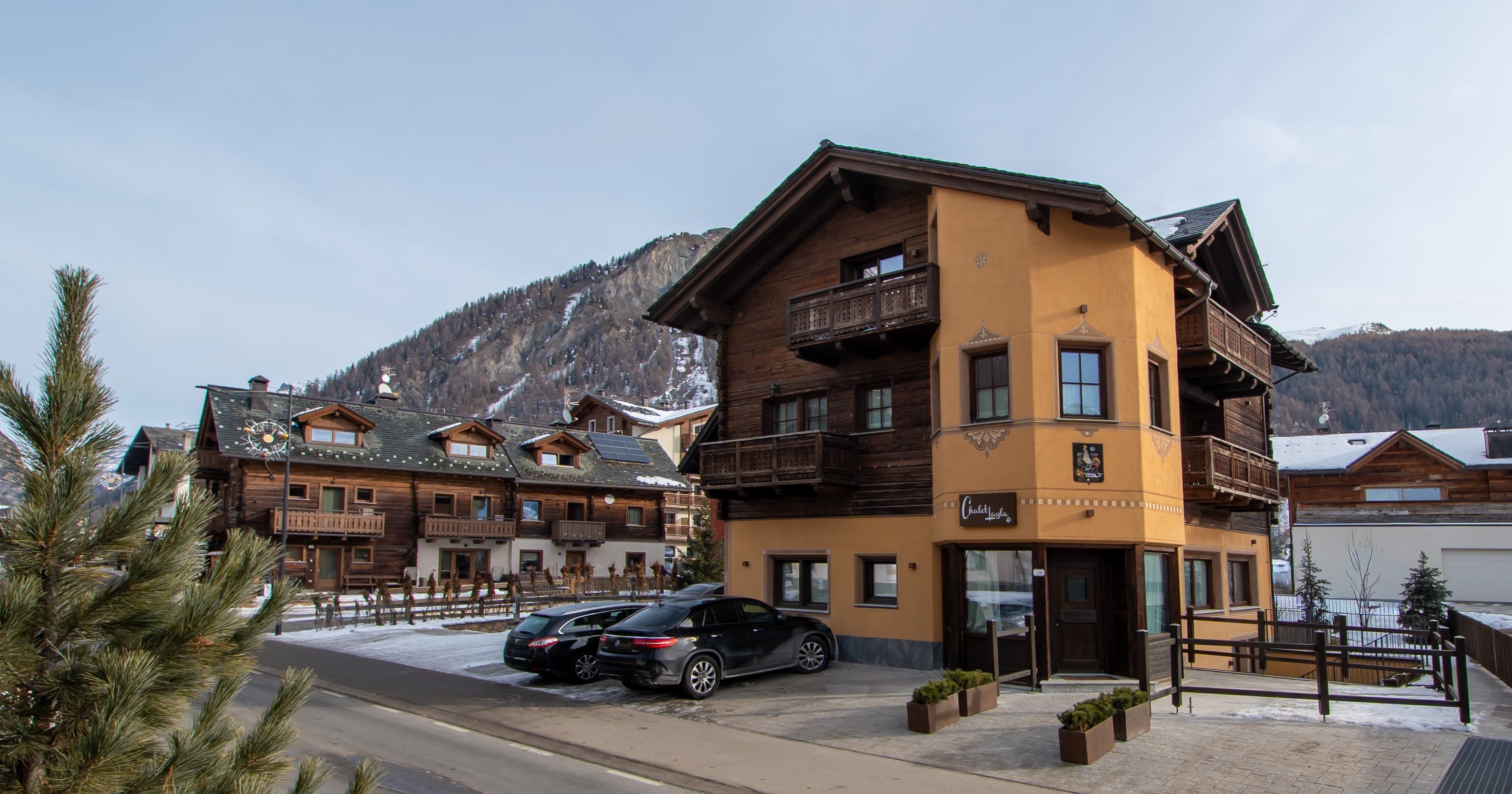 A multi-story hotel with a ski resort backdrop, featuring balconies and a ski lift in the background.