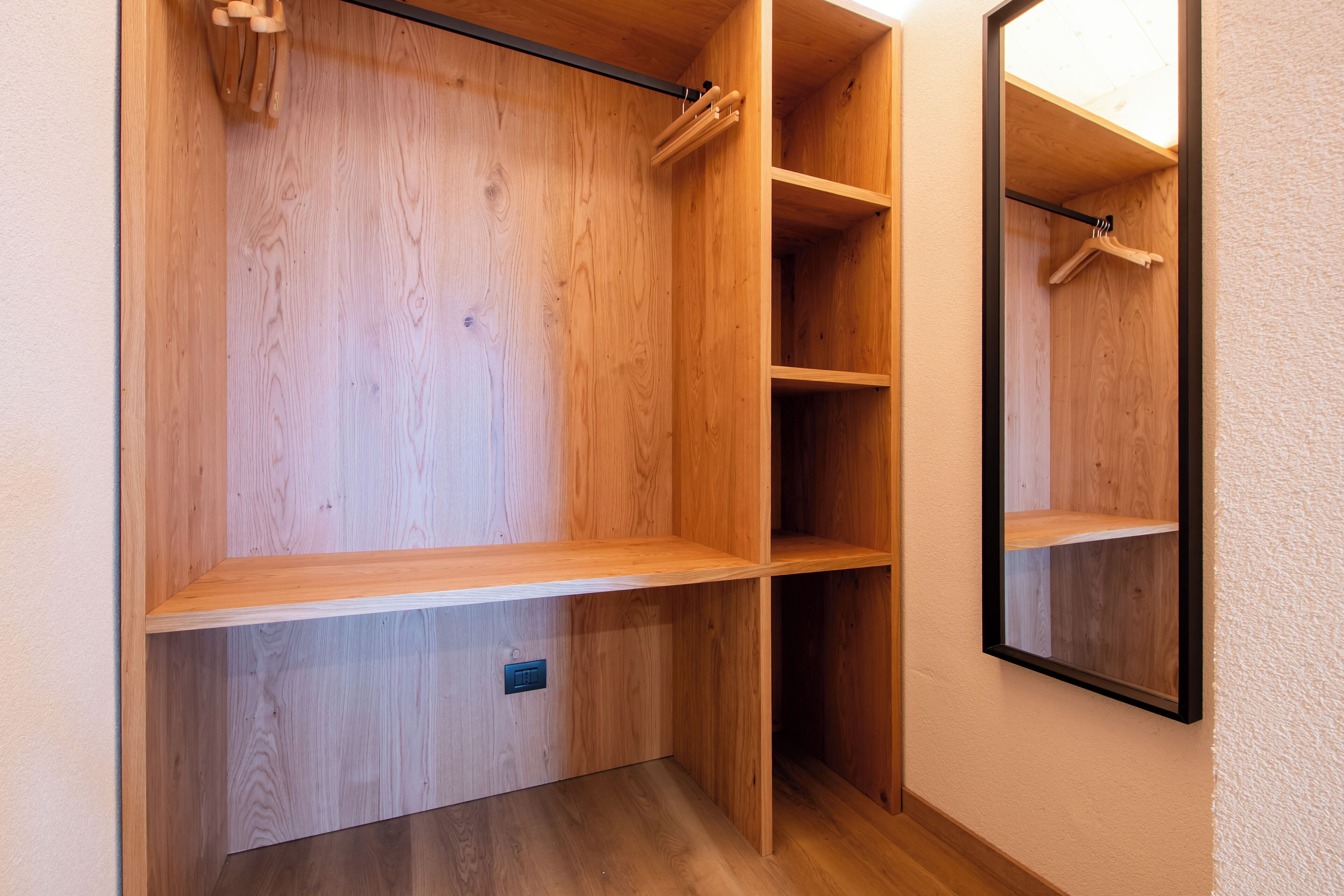Un placard en bois avec plusieurs étagères et un espace pour suspendre les vêtements.