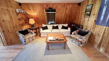 A wooden-paneled room with a sofa set, a coffee table, and a rug.
