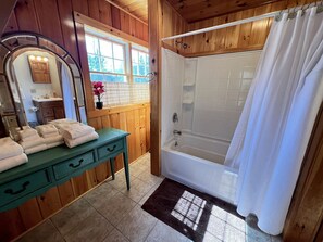 Une salle de bain avec un meuble-lavabo en bois, une baignoire et un rideau de douche.
