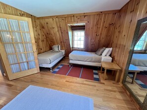 Een kamer met houten wanden, een bed, een bank, een kleine tafel en een raam.