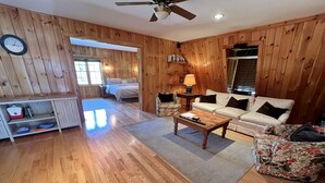 Quarto com painéis de madeira, uma cama, um sofá, uma mesa de centro e um abajur.