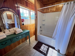 Een badkamer met een houten wastafelmeubel, een badkuip en een douchegordijn.