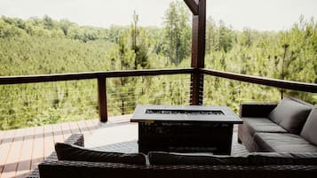 Una terrazza con un divano e un tavolo, con vista su una zona boschiva.