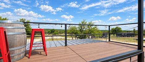 Une terrasse extérieure avec un plancher en bois, une rambarde en métal et un tabouret rouge.