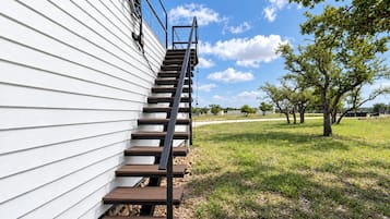 A wooden staircase leading up to a white building with a metal handrail.