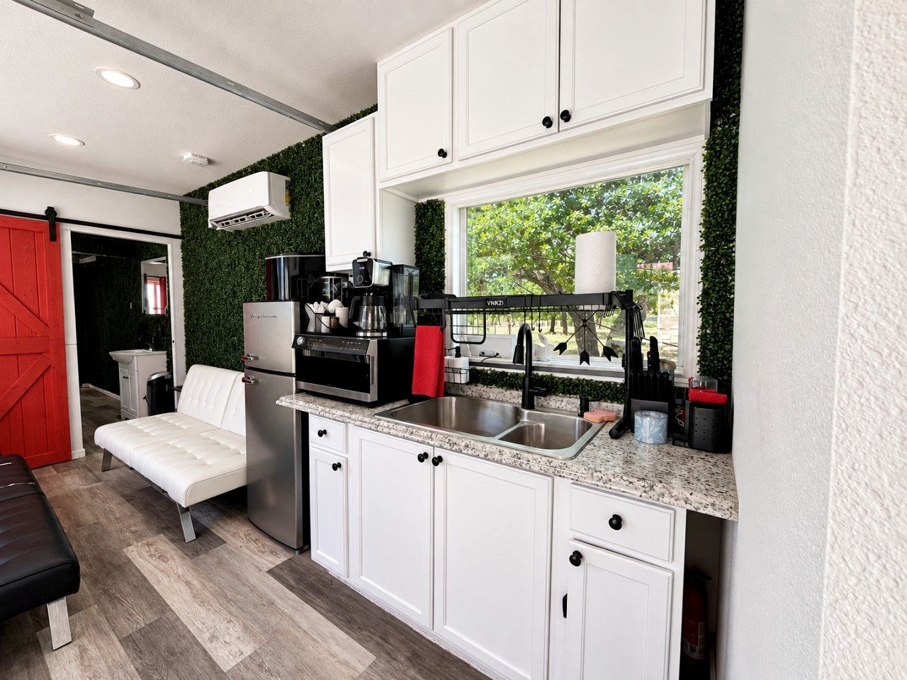A compact kitchen with white cabinets, a stainless steel refrigerator, and a countertop with various appliances.