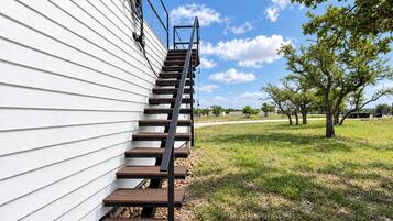 A wooden staircase leading up to a white building with a metal handrail.