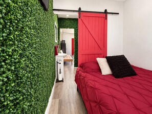 A bedroom with a red bed, a red sliding door, and a green wall. - Wonderful Secluded Container in Fredericksburg, Texas (Fredericksburg)