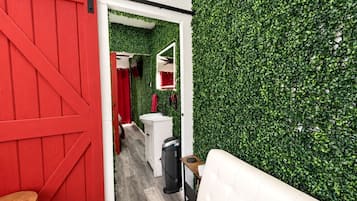 A room with a red barn door, a white sofa, and a green wall.
