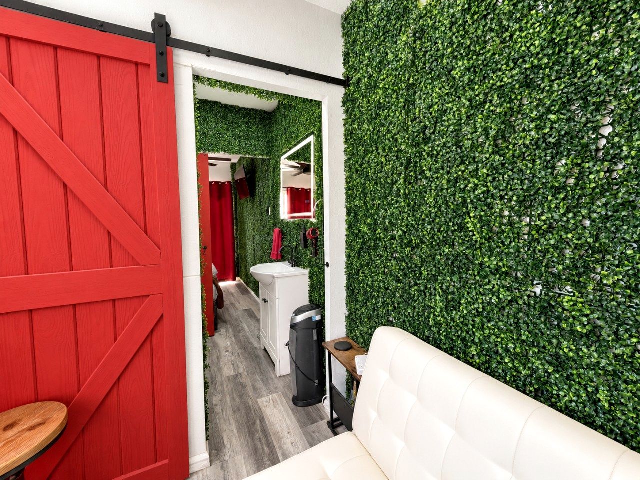 A room with a red barn door, a white sofa, and a green wall.