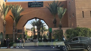 A building with a large archway and palm trees. There is a sign above the archway that reads "Qaryah Syahia". - 3-bedroom riad in amazing Marrakesh with fitness room, AC for family & friends (Marrakesh)