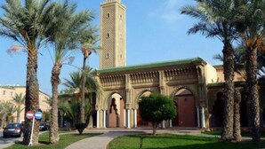 A building with a prominent tower, palm trees, and a clear sky. - 3-bedroom riad in amazing Marrakesh with fitness room, AC for family & friends (Marrakesh)