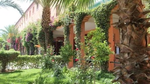 A building with a garden, palm trees, and a cross symbol. - 3-bedroom riad in amazing Marrakesh with fitness room, AC for family & friends (Marrakesh)