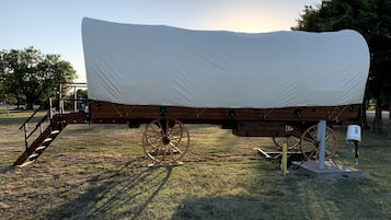 A covered wooden wagon with wheels, a wooden ramp, and a mailbox.