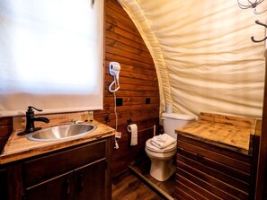 Une petite salle de bain avec un meuble-lavabo en bois, un évier, des toilettes et un sèche-cheveux fixé au mur.