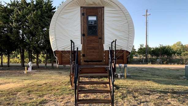 Une structure en bois abritée, dotée d’une porte et d’un escalier menant à l’intérieur.