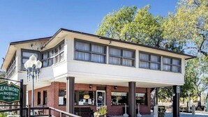 Een hotel met twee verdiepingen, een plat dak, een overdekte veranda en een naambord.