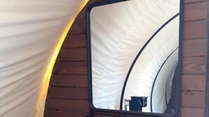 Une structure en forme de tente, avec un intérieur en bois, un miroir et une serviette accrochée au mur.