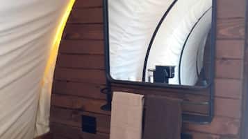 A tent-like structure with a wooden interior, a mirror, and a towel hanging on the wall.