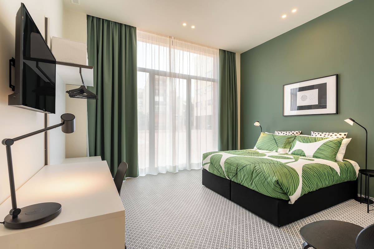 A modern hotel room with a bed, desk, and chair.