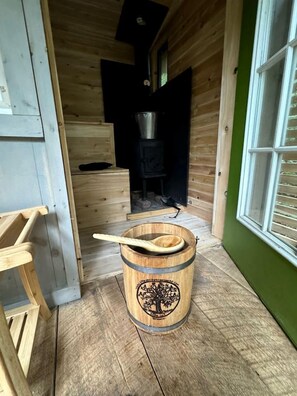 A wooden interior with a wooden barrel, a wooden spoon, and a stove. - Cozy Treehouse with Sauna in Hardwick, VT (Hardwick)
