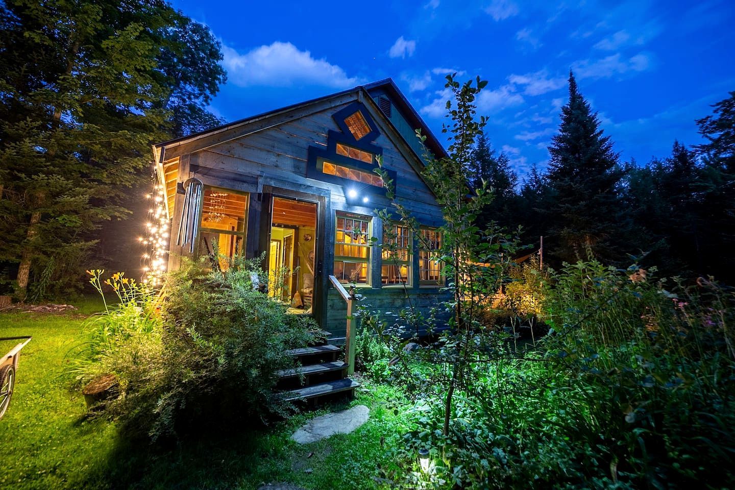 A rustic cabin with a wooden exterior, a porch, and a well-lit entrance.