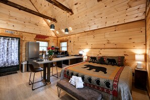 Ein Cabin-Innenraum mit einem Bett, einem Schreibtisch, einem Sessel, einer kleinen Küchenzeile und einem Badezimmer.