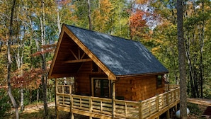 A wooden cabin with a porch, surrounded by trees in autumn colors. - Stunning Cabin Nestled Amidst Trees with Hot-tub in Sevierville, Tennessee (Sevierville)