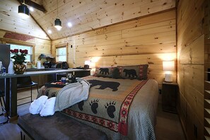Um quarto acolhedor estilo cabana, com cama, mesas de cabeceira, escrivaninha e uma cadeira.