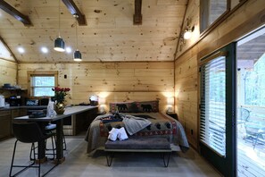 A cabin with a kitchen, dining area, and a bedroom with a bed, bench, and window. - Stunning Cabin Nestled Amidst Trees with Hot-tub in Sevierville, Tennessee (Sevierville)