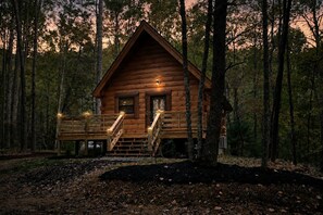Eine Holzhütte mit Veranda, Treppen und einer Lampe.