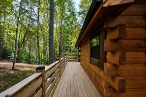 Uma cabana de madeira com um deck que se estende até a floresta.