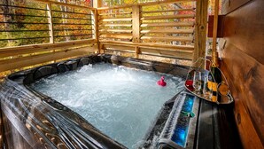 A hot tub with a wooden exterior and a view of autumn foliage. - Stunning Cabin Nestled Amidst Trees with Hot-tub in Sevierville, Tennessee (Sevierville)