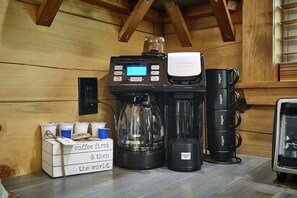 Eine Kaffeemaschine mit digitaler Anzeige, eine Kaffeekanne und eine weitere Kaffeemaschine auf einer Holzauskład.