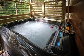 Ein Whirlpool mit Bedienfeld, umgeben von Holzgeländern und Blick auf Bäume.