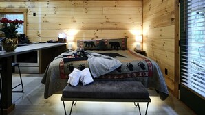 Una camera in legno con un letto, un comodino e una panca.