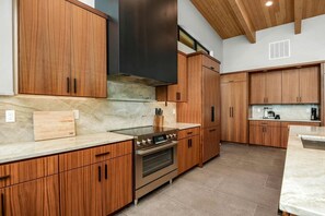 Eine moderne Küche mit Holzschränken, einem Edelstahlbackofen und einer Marmorarbeitsplatte.