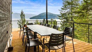 Une terrasse avec une table et des chaises donnant sur un lac et des montagnes.