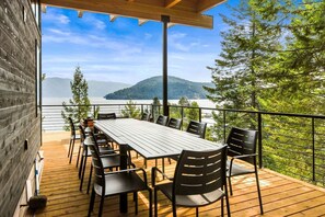 Une terrasse avec une table et des chaises donnant sur un lac et des montagnes.