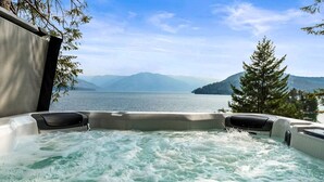 A hot tub with a view of a lake and mountains.