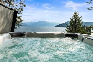 A hot tub with a view of a lake and mountains.