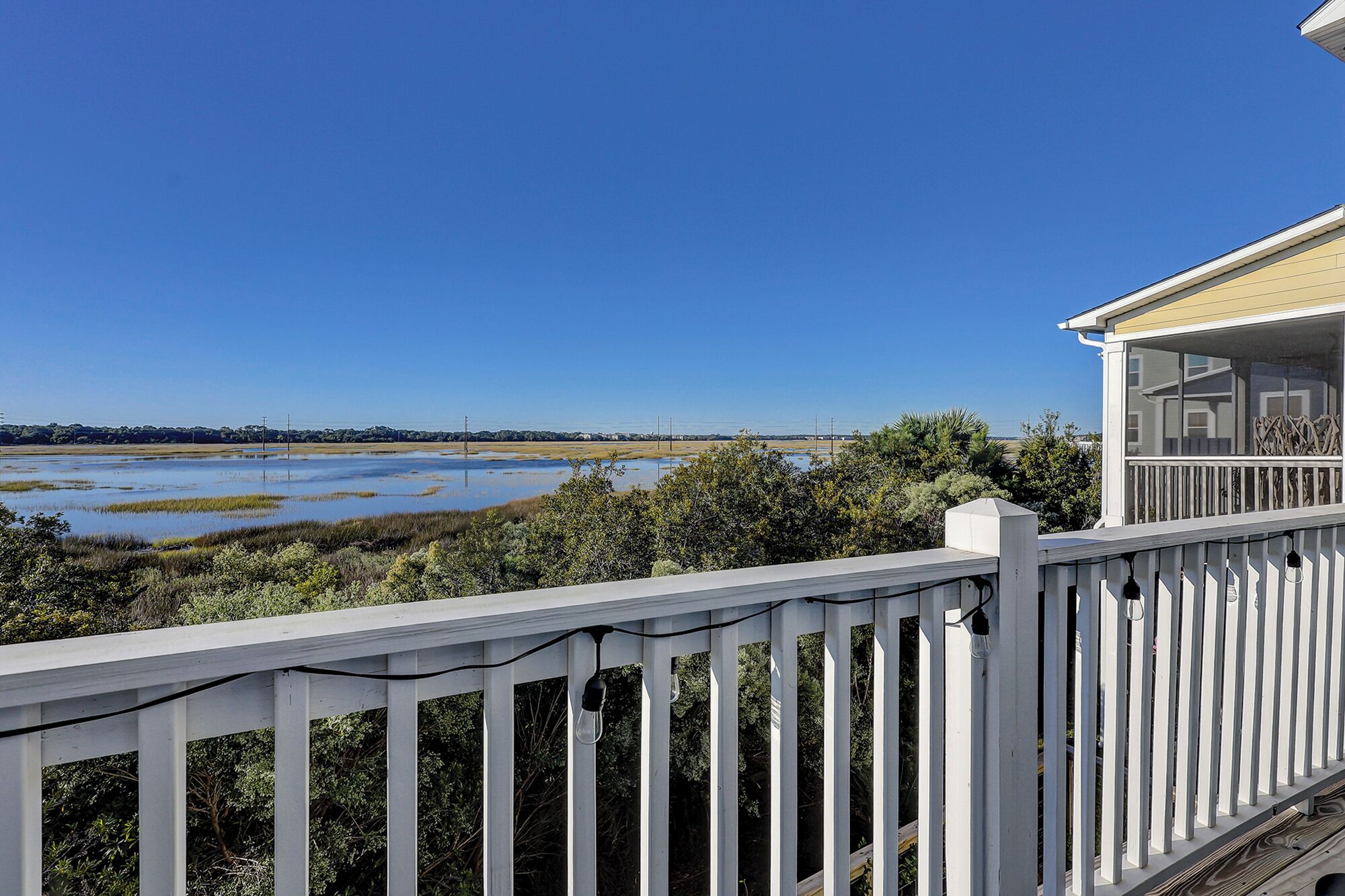 Un balcon donnant sur un paysage marécageux et un ciel bleu dégagé.