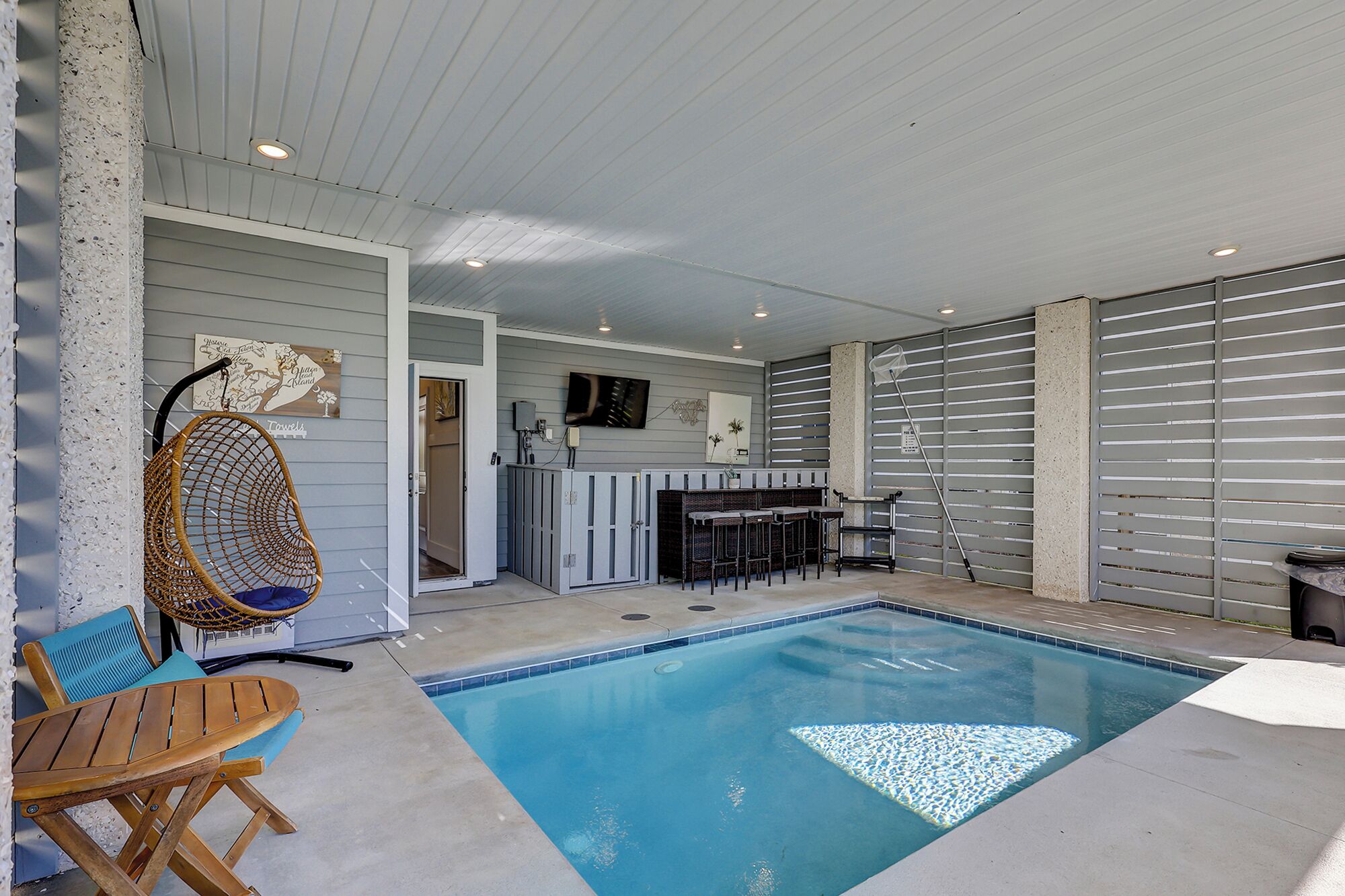 Una piscina interior con zona de estar, un televisor y un mapa en la pared.