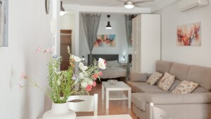 En moderne stue med en hvid sofa, et lille sofabord og en blomstervase.