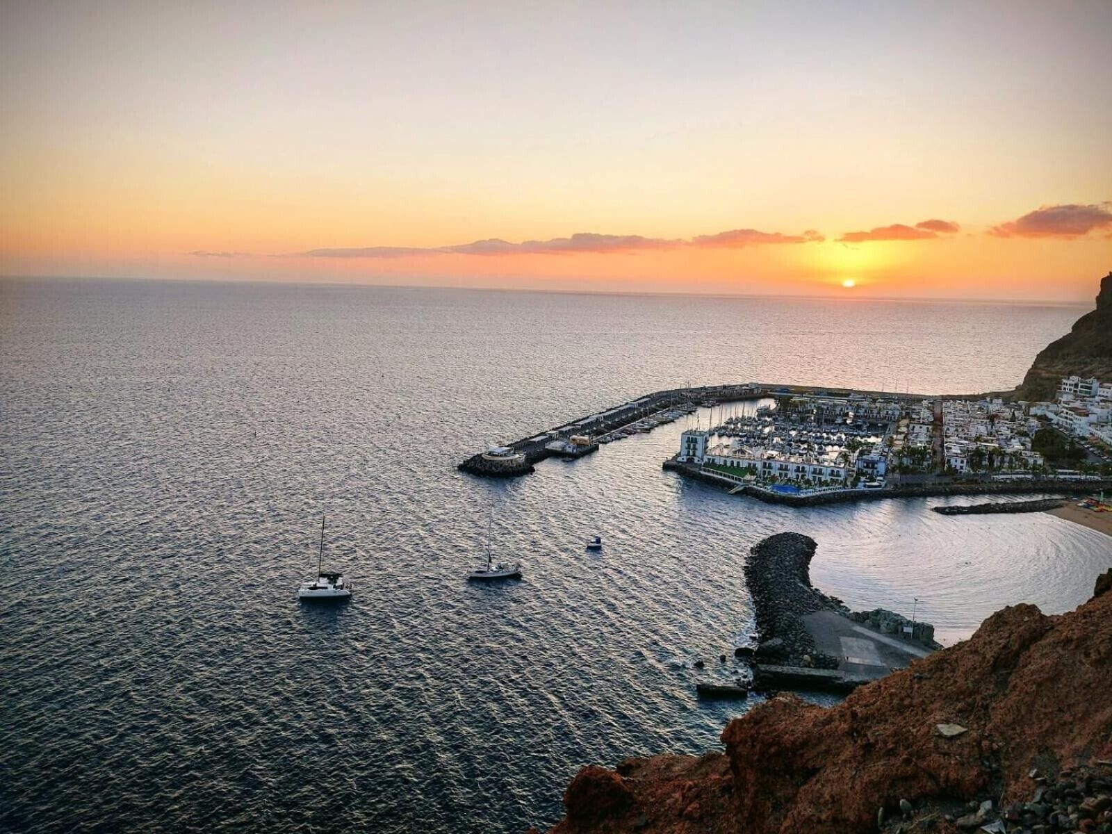 A coastal town with a marina, boats, and a sunset.