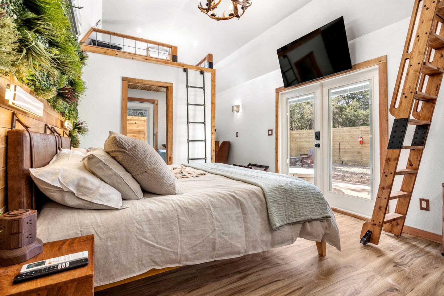 Ein Schlafzimmer mit Hochbett, Wandfernseher, einer Leiter und Blick ins Freie.